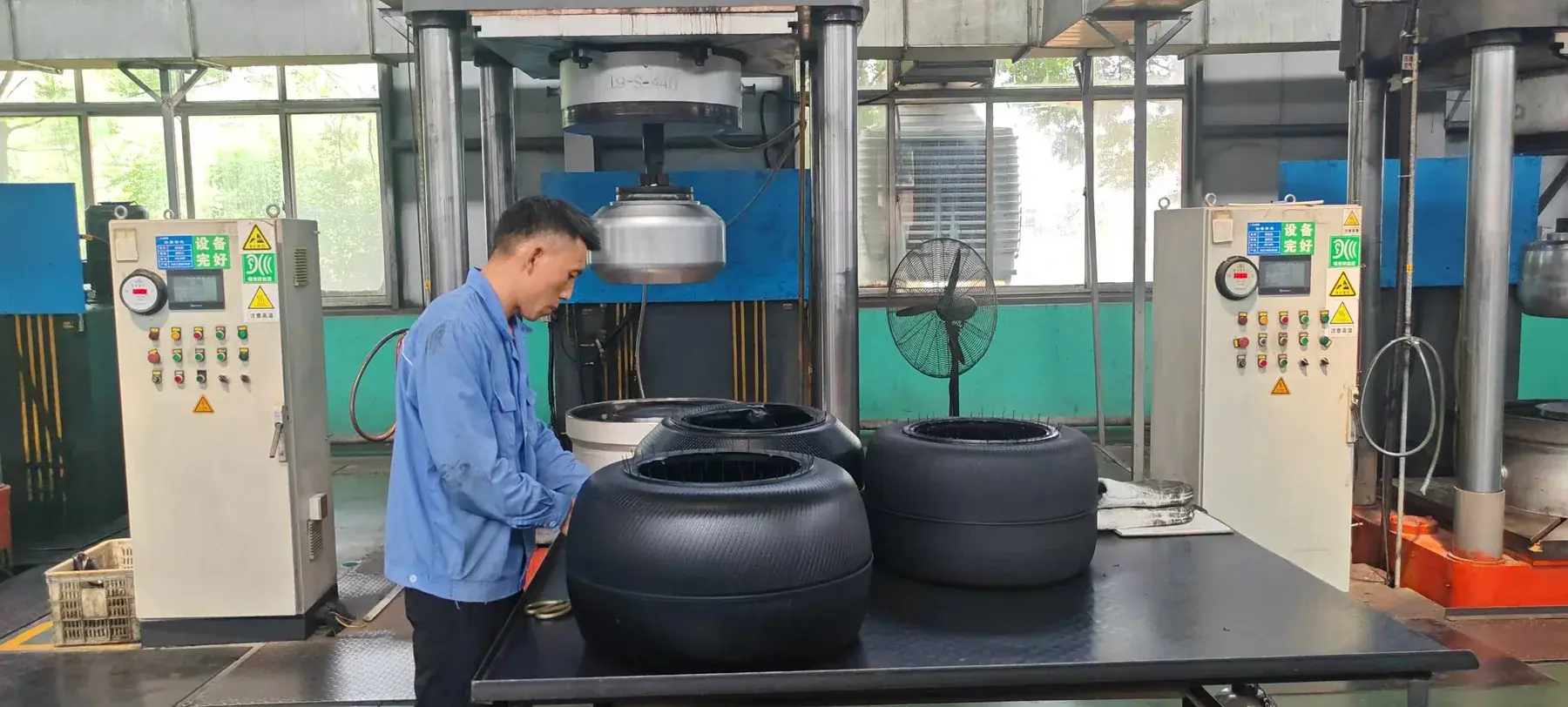Authorized photograph of a worker and tire curing bladders at Yongyi Rubber molding equipment